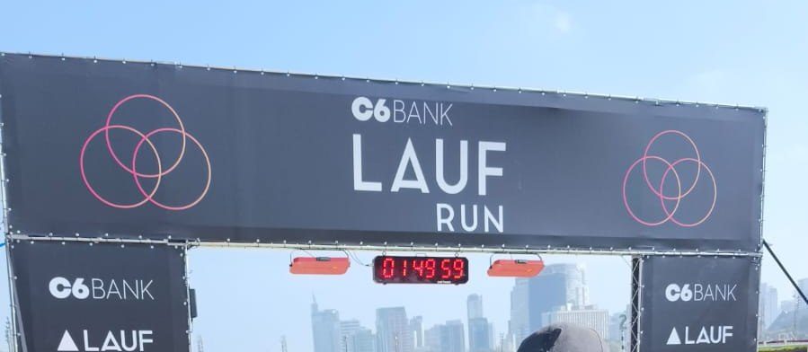 Pórtico do C6 Bank Lauf Run com relógio de prova e o skyline de São Paulo